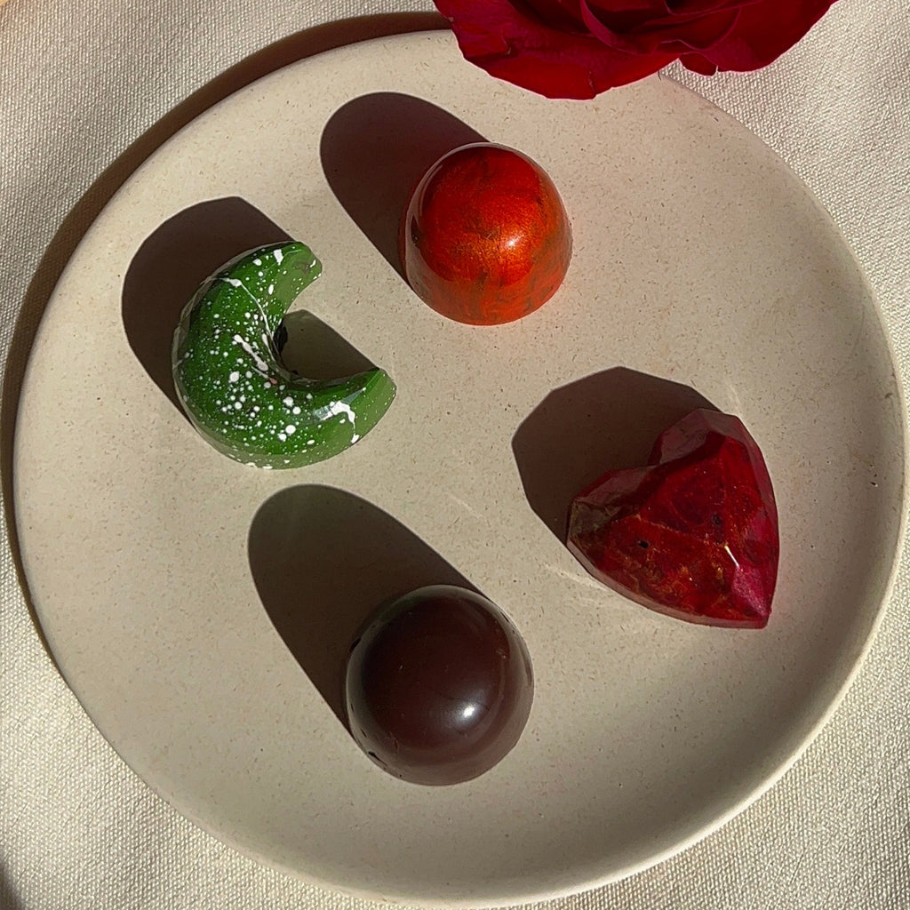 Six-piece selection of handcrafted, plant-based chocolate bonbons with unique flavors, each reflected in its shape and design.