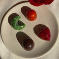 Six-piece selection of handcrafted, plant-based chocolate bonbons with unique flavors, each reflected in its shape and design.