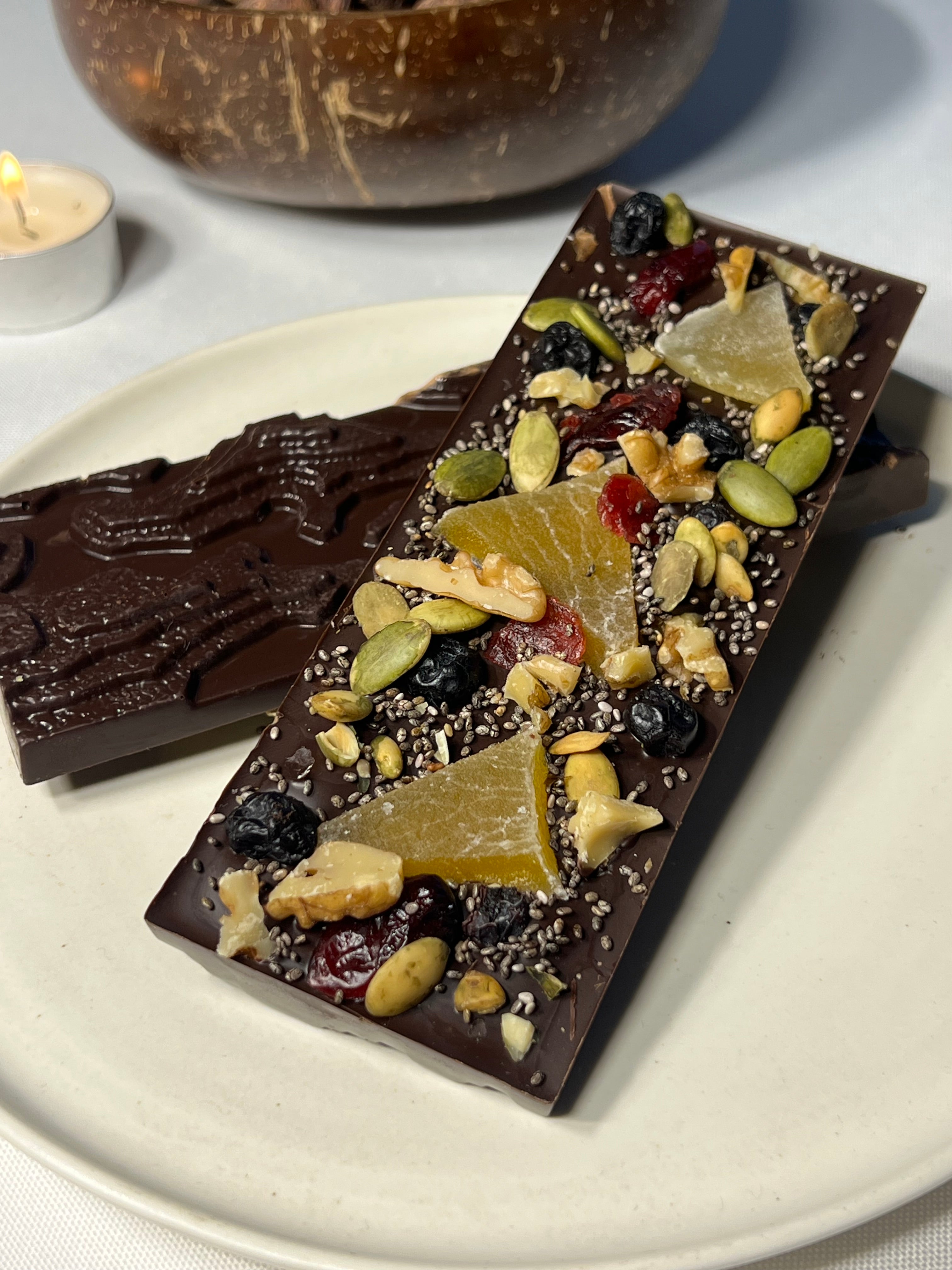 Handcrafted 64% single-origin dark chocolate bar in Infinite Pâtisserie's signature topography mold, topped with walnuts, dried mango, blueberries, cranberries, pumpkin seeds, and chia seeds.