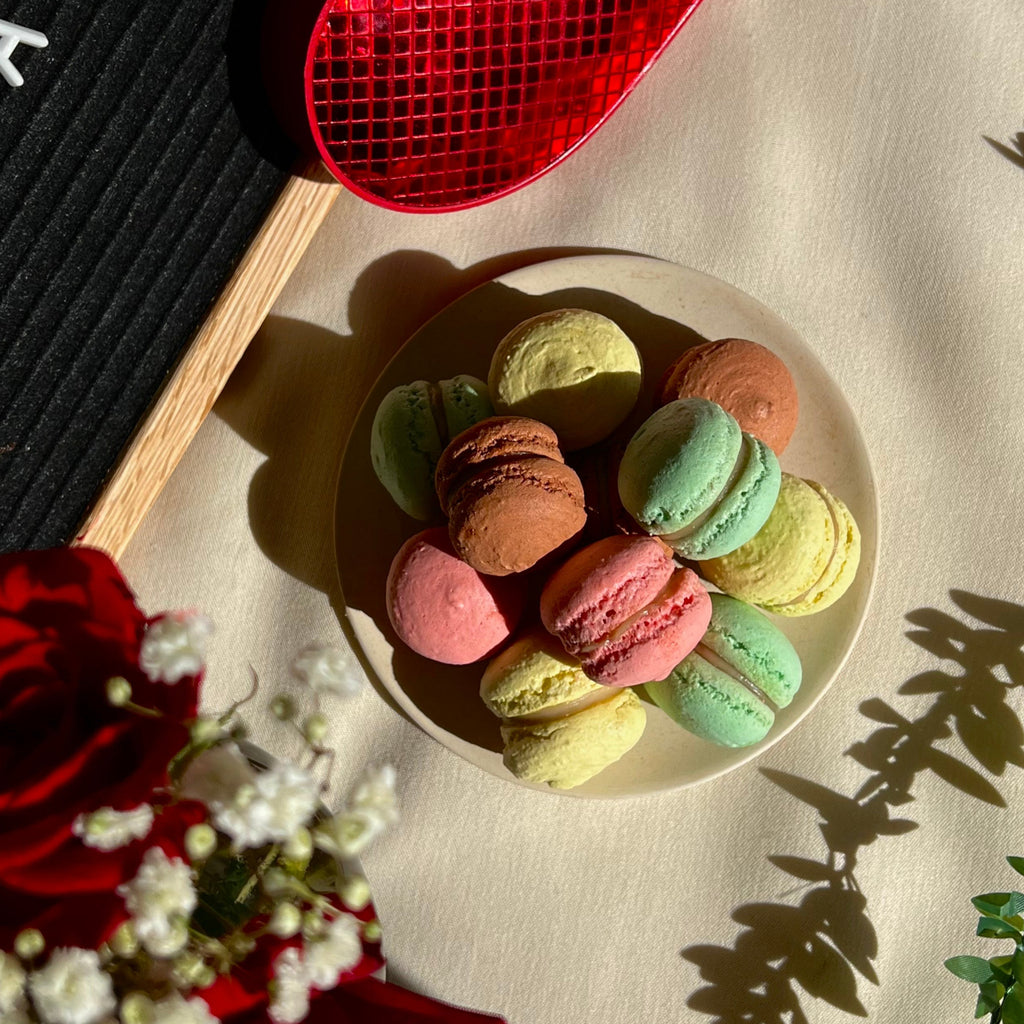 Assortment of handcrafted macarons displayed on a plate, showcasing a variety of colors and flavors.