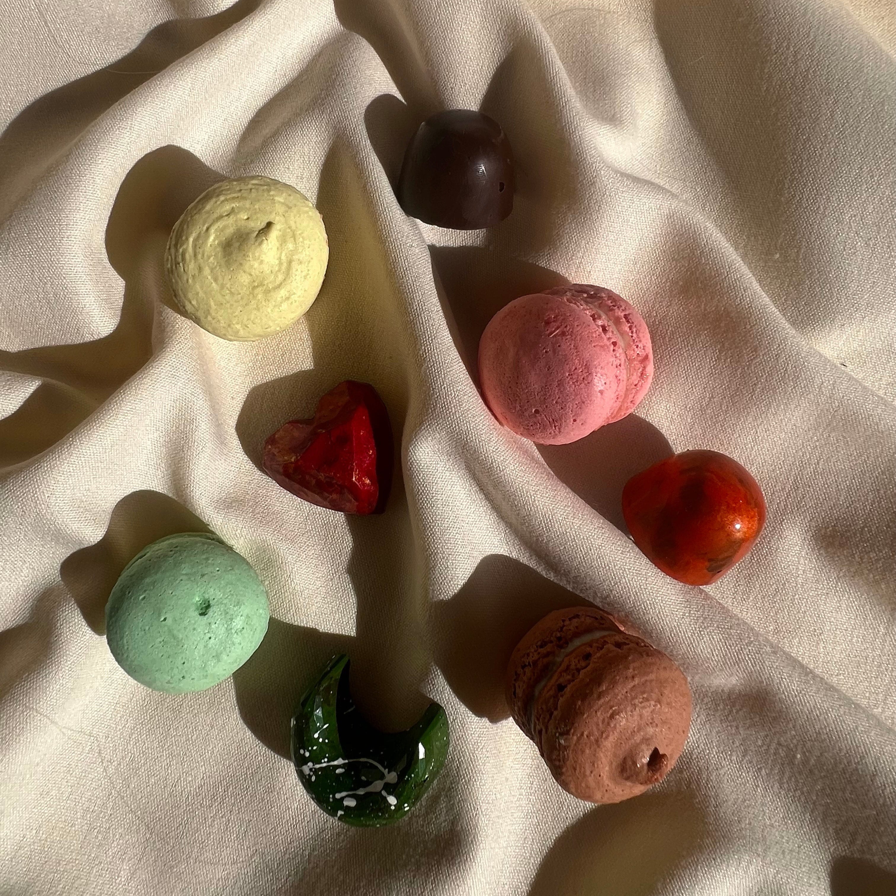 Curated selection of four bonbons and four macarons, each handcrafted with distinct colors and shapes, displayed on a cream linen.