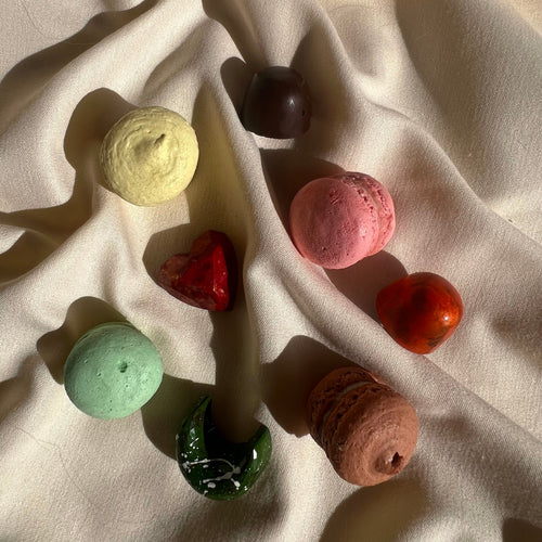 Curated selection of four bonbons and four macarons, each handcrafted with distinct colors and shapes, displayed on a cream linen.